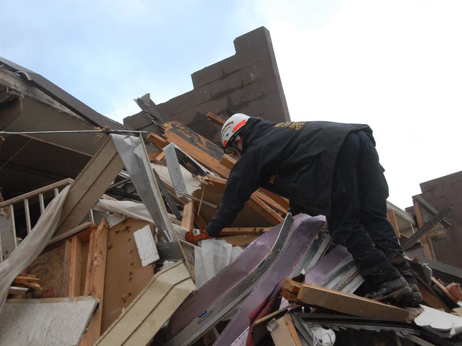 A rescuer searching the remains of a home destroyed by a storm