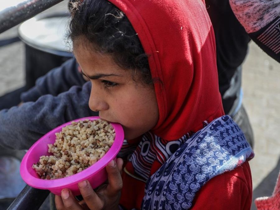 A child in Gaza eating hot food from a bowl