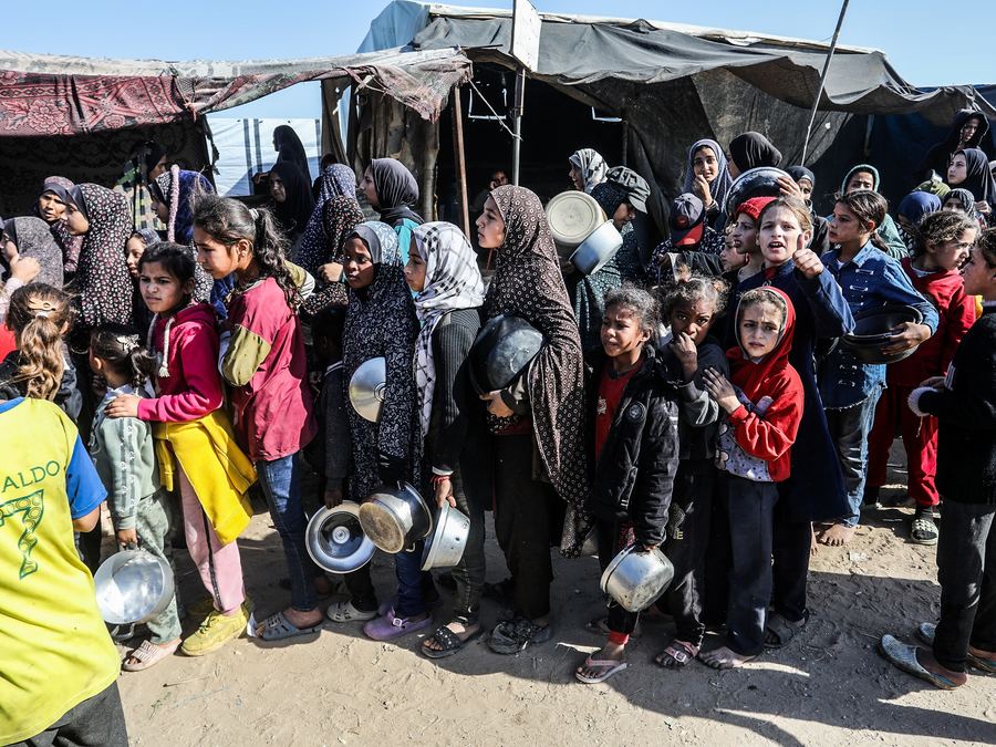 Children and families in Gaza waiting in line for food with pots in hand