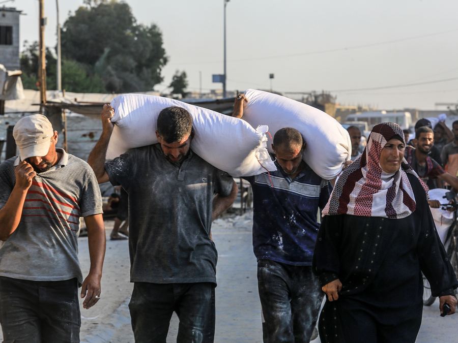 People in Palestine carrying sacks of flour on their shoulders