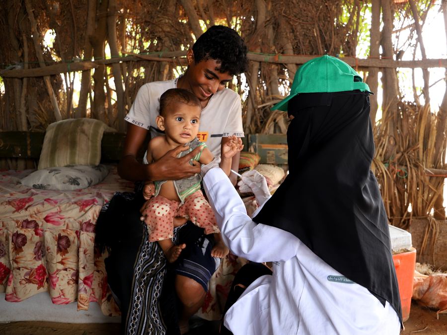 A family in Yemen receiving aid, a baby in their arms