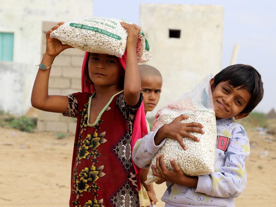 Smiling children in Yemen carrying food supplies