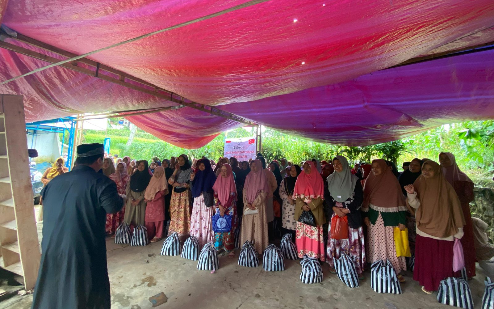 Families receiving food parcels under a tent